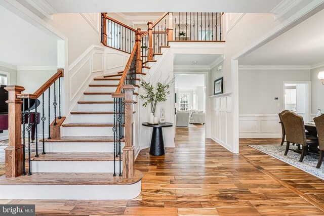 11304 Chivalry Chase Ln, Spotsylvania, VA 22551 - staircase with wood finished floors, ornamental molding, a wainscoted wall, a towering ceiling, and a decorative wall