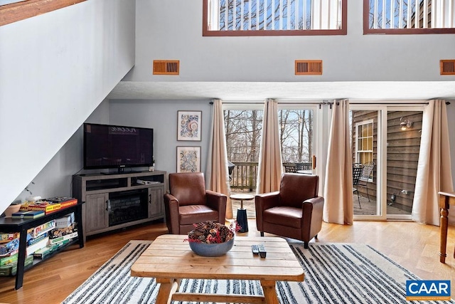 16 Chestnut Ln, Wintergreen Resort, VA 22967 - living room featuring visible vents, wood finished floors, a fireplace, and a high ceiling
