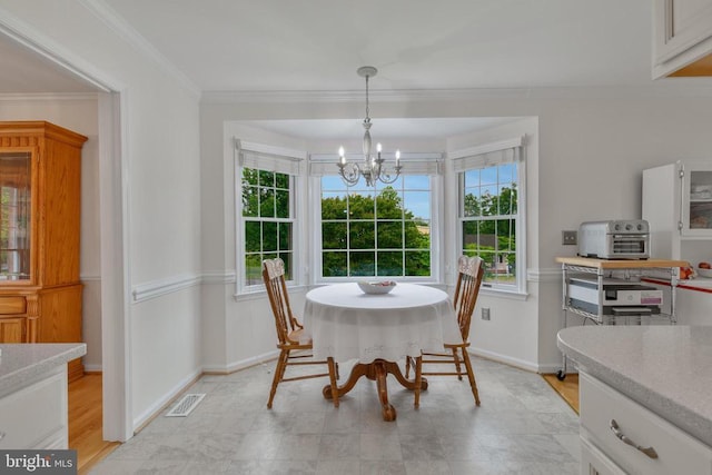 dining space with a chandelier, crown molding, and baseboards