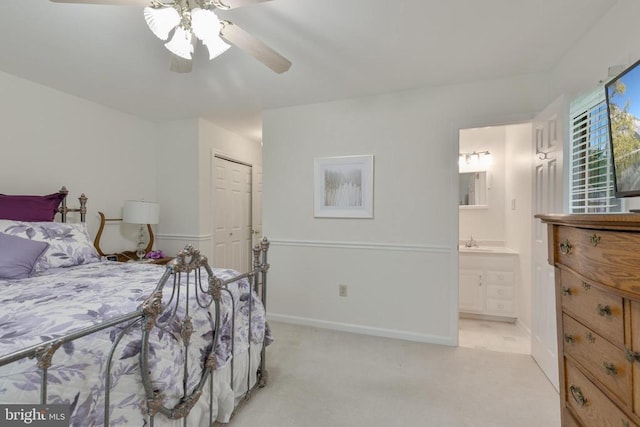 bedroom featuring a sink, light carpet, a closet, ensuite bathroom, and baseboards
