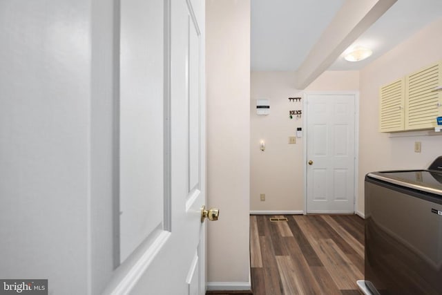 clothes washing area featuring dark wood finished floors, washer / dryer, and baseboards