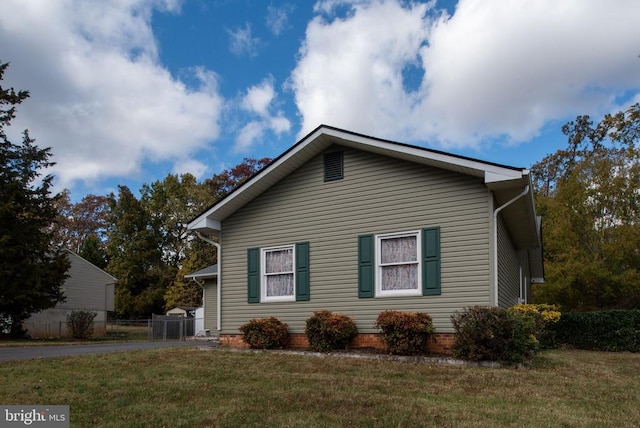 view of home's exterior featuring a lawn, driveway, and fence