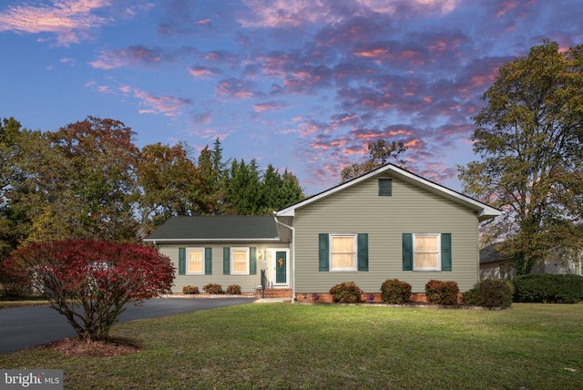 ranch-style home with aphalt driveway and a front yard