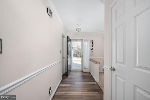 doorway featuring dark wood-type flooring, baseboards, visible vents, and ornamental molding