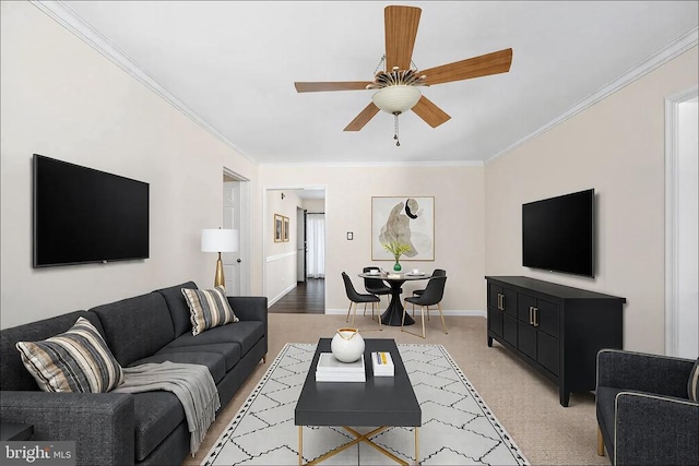 living area featuring light colored carpet, baseboards, a ceiling fan, and ornamental molding