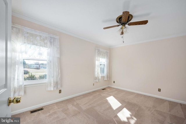 carpeted spare room with crown molding, baseboards, visible vents, and ceiling fan