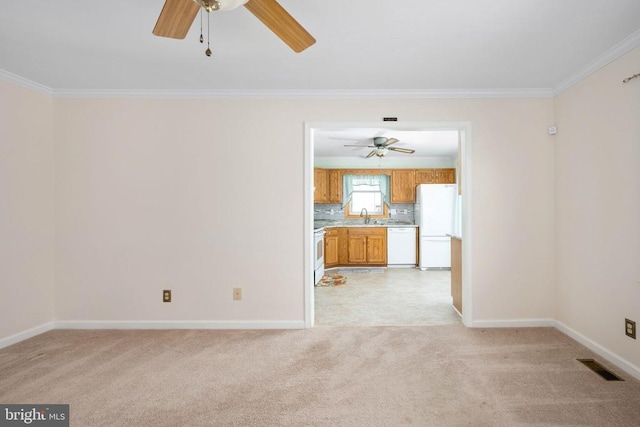 unfurnished living room featuring visible vents, light carpet, a sink, crown molding, and baseboards