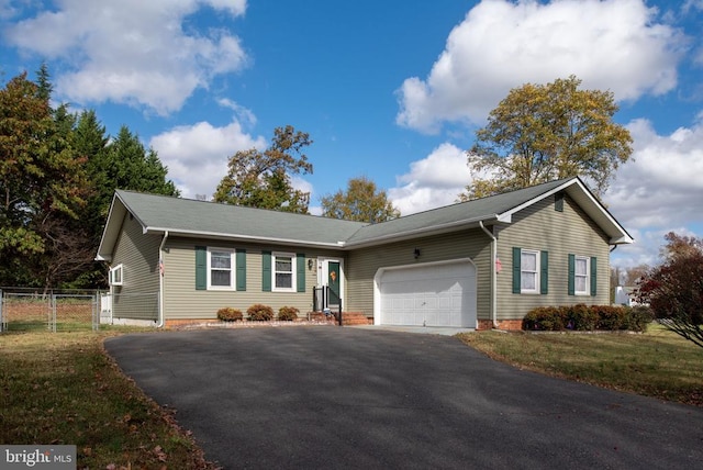 ranch-style home featuring aphalt driveway, an attached garage, fence, and a front yard