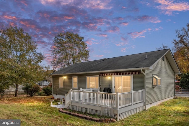 back of property with crawl space, a lawn, a deck, and fence