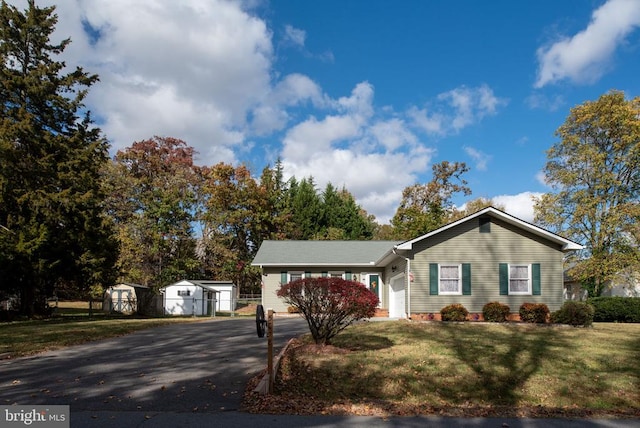 ranch-style house with aphalt driveway, a garage, and a front lawn