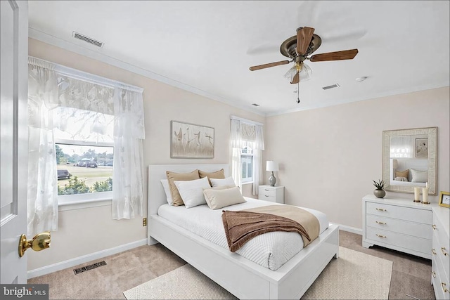 carpeted bedroom with visible vents, baseboards, a ceiling fan, and crown molding