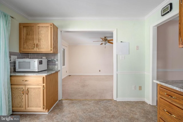 kitchen with white microwave, baseboards, light colored carpet, light countertops, and ornamental molding