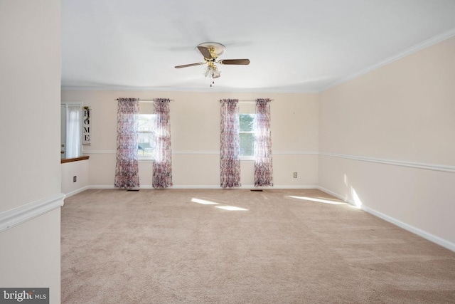 carpeted spare room with crown molding, a ceiling fan, and baseboards