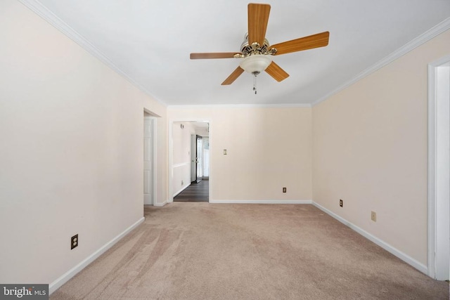 carpeted empty room with ceiling fan, crown molding, and baseboards