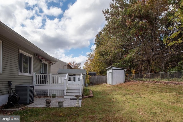 view of yard with a wooden deck, cooling unit, a fenced backyard, an outbuilding, and a storage unit