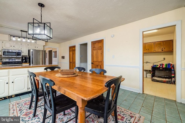 dining area with dark tile patterned floors and a textured ceiling