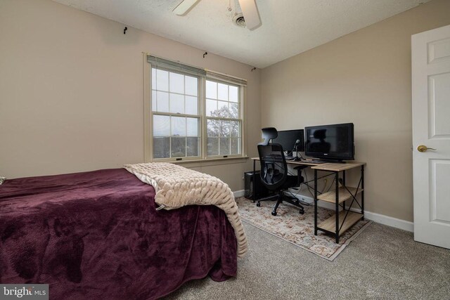 carpeted bedroom with baseboards, ceiling fan, and a desk