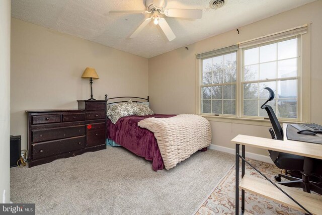 carpeted bedroom featuring a desk, multiple windows, a textured ceiling, a ceiling fan, and baseboards
