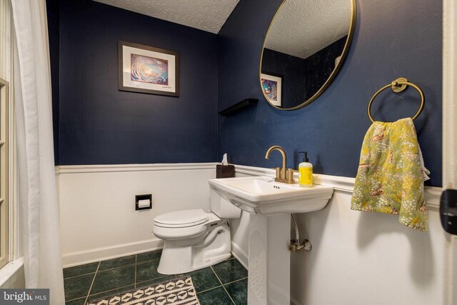 bathroom featuring tile patterned floors, toilet, and a textured ceiling