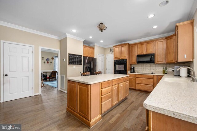 5819 Telluride Ln, Spotsylvania, VA 22553 - kitchen featuring black appliances, a sink, ornamental molding, wood finished floors, and a center island