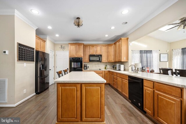 5819 Telluride Ln, Spotsylvania, VA 22553 - kitchen with black appliances, a sink, crown molding, a peninsula, and light countertops