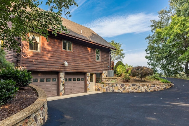1003 Natural Chimneys Rd, Mount Solon, VA 22843 - view of side of home with roof with shingles, central AC, driveway, a garage, and log exterior