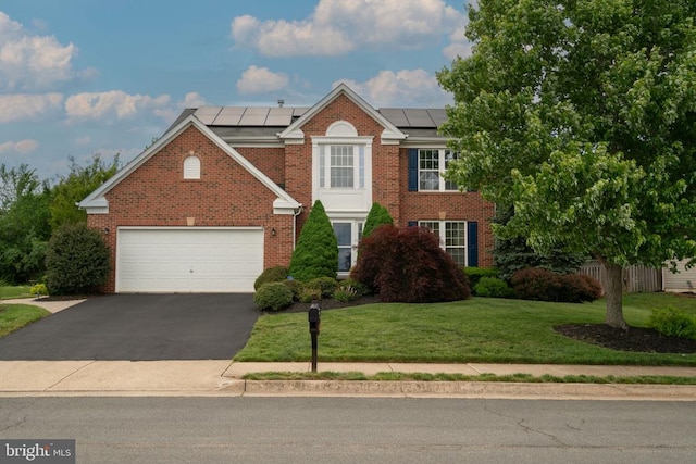 view of front of house with brick siding, driveway, a front lawn, and a garage