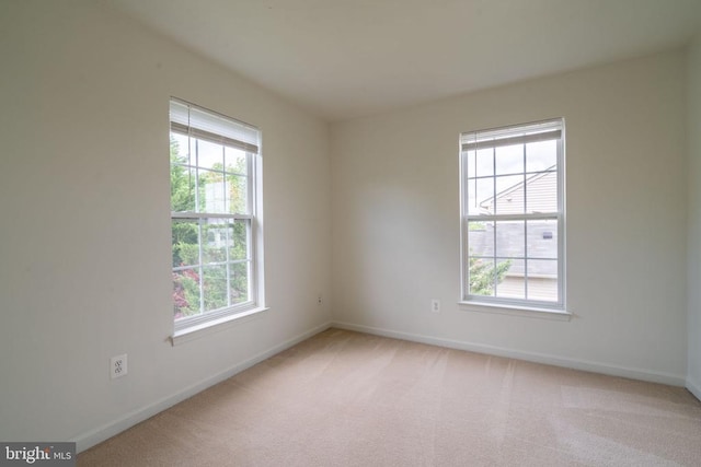 unfurnished room with healthy amount of natural light, baseboards, and light carpet