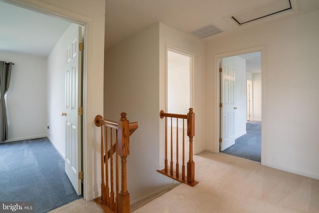 corridor with an upstairs landing, carpet, attic access, and baseboards