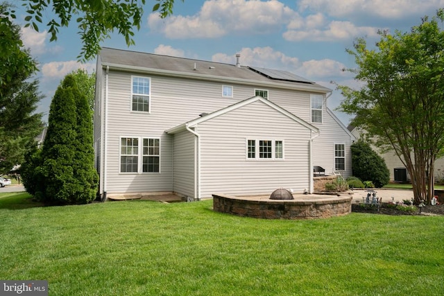 rear view of house with roof mounted solar panels, a yard, a patio area, and central AC