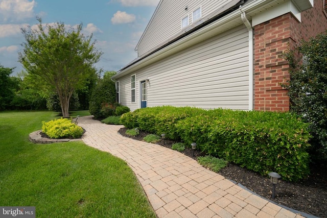 view of property exterior with a lawn and brick siding