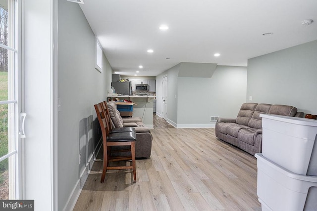 living area with baseboards, light wood-type flooring, visible vents, and recessed lighting