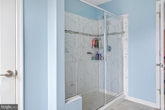 full bath with a marble finish shower and tile patterned flooring