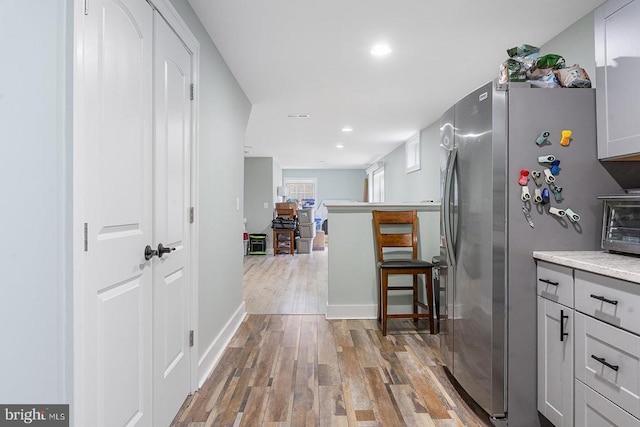 hallway featuring baseboards, recessed lighting, a toaster, and wood finished floors