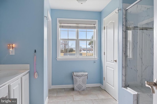 bathroom with a marble finish shower, baseboards, vanity, and tile patterned flooring
