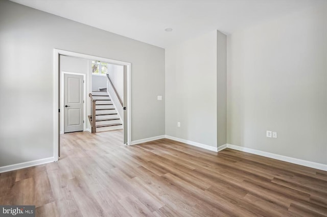  - empty room with light wood finished floors, baseboards, and stairway
