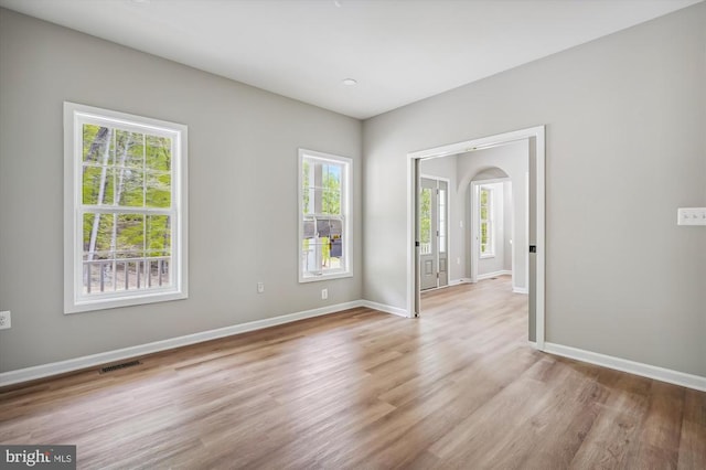  - unfurnished room featuring light wood-style flooring, baseboards, and arched walkways
