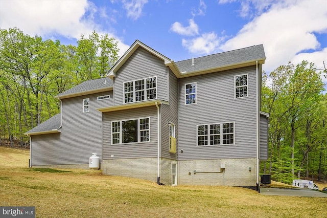  - rear view of property featuring a lawn, cooling unit, and a shingled roof