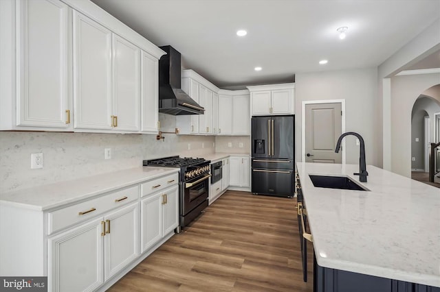  - kitchen featuring black refrigerator with ice dispenser, range with gas cooktop, a sink, wall chimney range hood, and recessed lighting