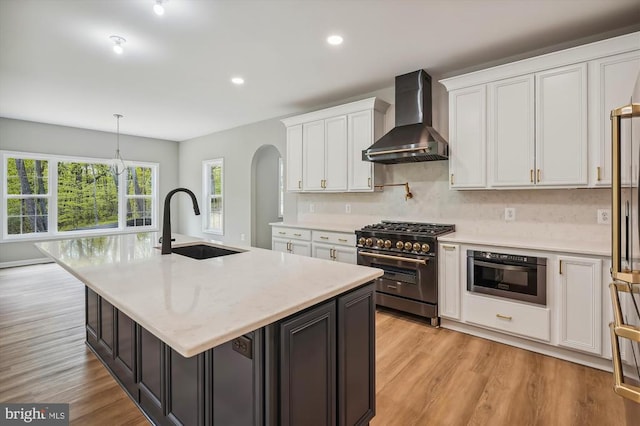  - kitchen with stainless steel appliances, wall chimney range hood, a sink, white cabinets, and recessed lighting