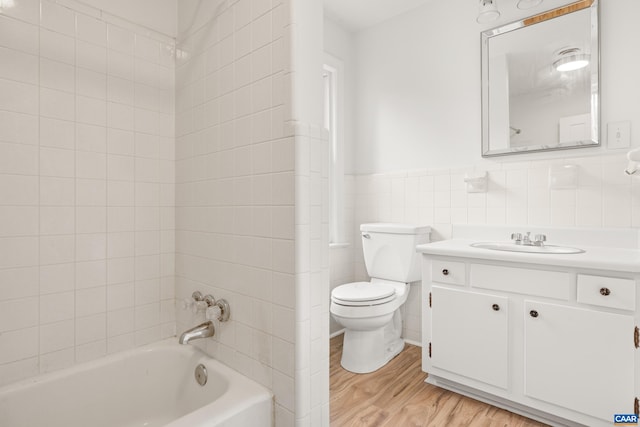 7928 Howardsville Rd, Scottsville, VA 24562 - bathroom featuring vanity, wood finished floors, tile walls, washtub / shower combination, and a wainscoted wall