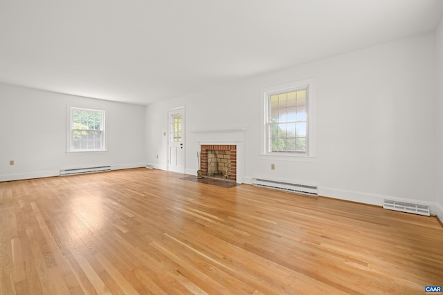 7928 Howardsville Rd, Scottsville, VA 24562 - unfurnished living room featuring a baseboard heating unit, light wood finished floors, and a brick fireplace