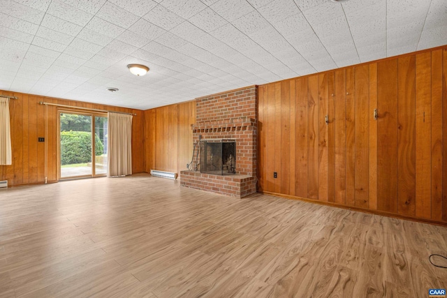7928 Howardsville Rd, Scottsville, VA 24562 - unfurnished living room featuring wooden walls, wood finished floors, baseboard heating, and a brick fireplace