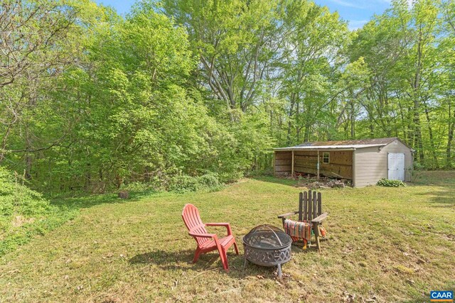 1842 Ed Jones Rd, Scottsville, VA 24590 - view of green lawn featuring an outdoor fire pit, an outbuilding, a storage unit, and a forest view