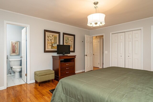 bedroom featuring ornamental molding, a closet, baseboards, wood finished floors, and connected bathroom