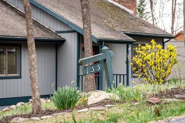 entrance to property with a shingled roof and a chimney
