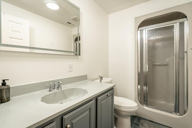 bathroom with a stall shower, vanity, and toilet