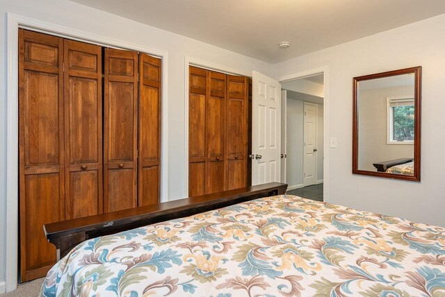 bedroom with baseboards and two closets