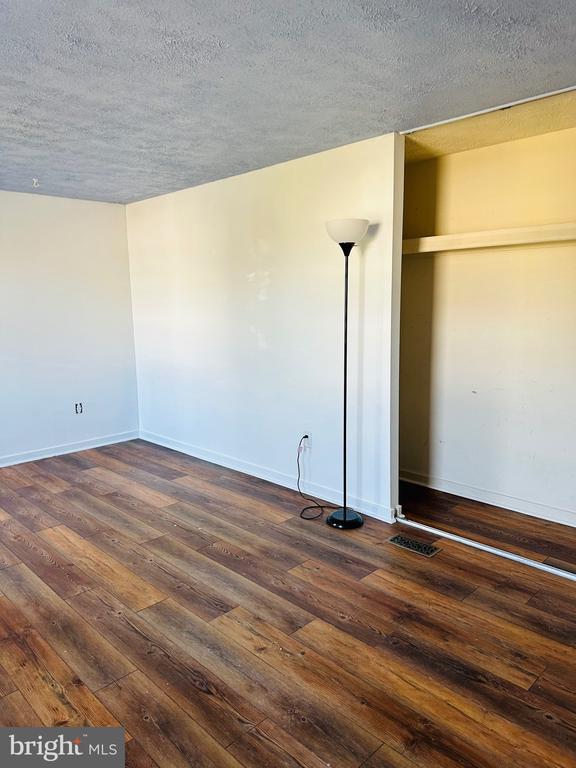 unfurnished bedroom featuring dark wood-style floors, baseboards, and a textured ceiling