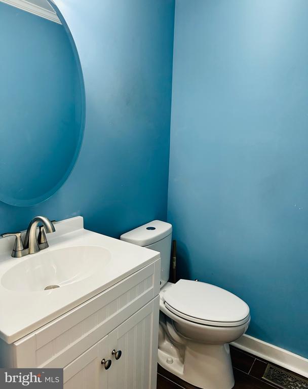 half bathroom with baseboards, toilet, and vanity